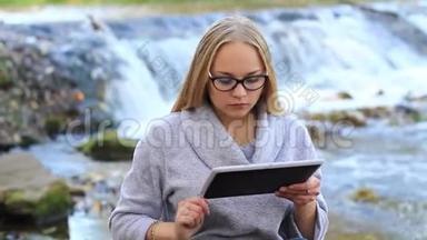 女孩用<strong>笔记本</strong>电脑工作，在瀑布附近吃<strong>苹果</strong>